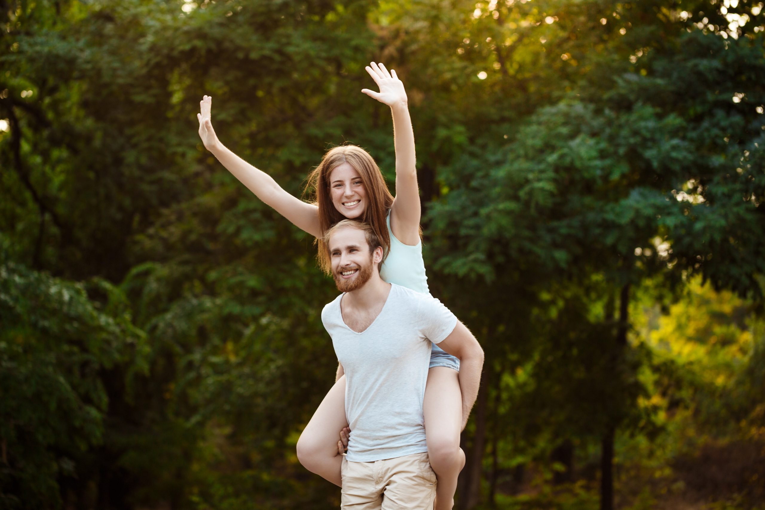 Young beautiful couple resting, walking in park, smiling, rejoicing. Outdoor background.